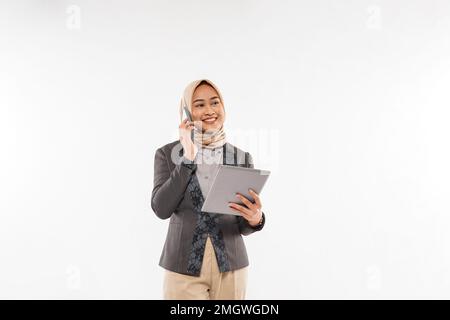 une femme avec hijab debout avec le sourire et appelant quelqu'un au téléphone Banque D'Images