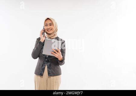une jeune femme avec hijab debout et appelant quelqu'un au téléphone Banque D'Images