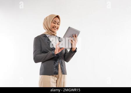 une femme avec hijab et blazzer gris debout regardant la tablette Banque D'Images