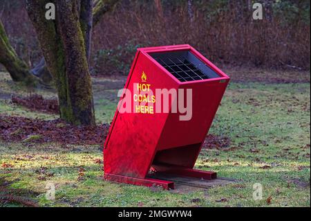 Réceptacle à charbon rouge vif avec inscriptions jaunes dans l'aire de pique-nique d'un parc local - Maple Ridge, B. C., Canada. Banque D'Images