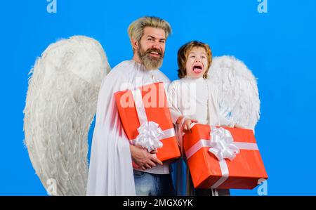 Saint-Valentin. Petit cupidon et barbu dans des ailes d'ange avec cadeau de Valentin. Père et fils. Banque D'Images