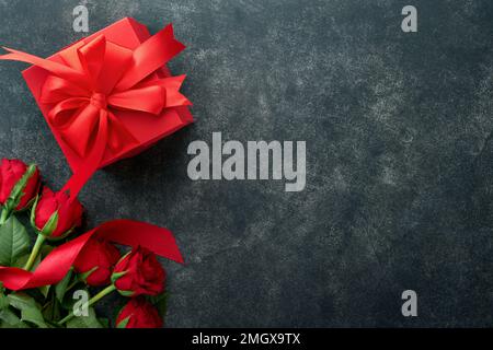 Biscuits au velours rouge ou au brownie sur le coeur en forme de glaçage au chocolat avec roses rouges et boîte cadeau sur fond noir. Idée de dessert pour la Saint-Valentin, Mot Banque D'Images