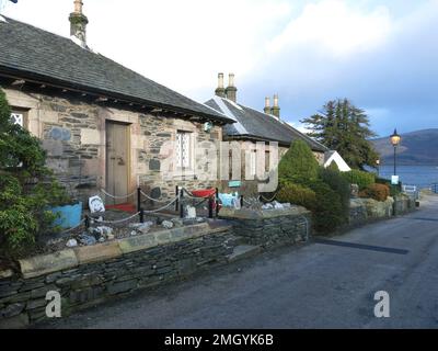 Une rangée de chalets en pierre dans Pier Road dans le village de conservation de Luss sur les rives occidentales du Loch Lomond, une destination touristique populaire. Banque D'Images