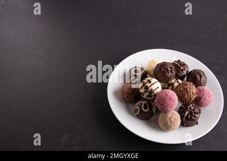 photo sur une assiette il y a des chocolats sur fond noir Banque D'Images