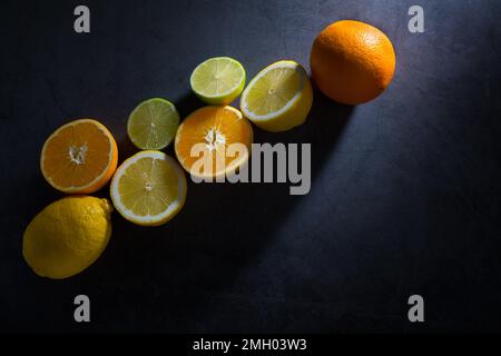 Agrumes frais mûrs. Citrons, limes et oranges sur fond noir en foncé. Top View with copy space Banque D'Images