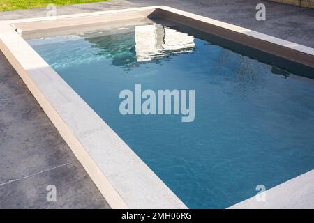 piscine privée familiale avec pierre faisant face à la terrasse en béton ciré gris bleu transparent Banque D'Images