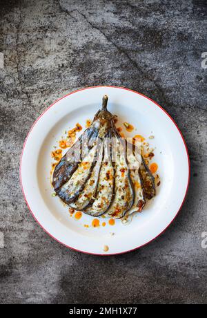 Aubergine cuite au four, vêtue de harissa et de pistache. Banque D'Images