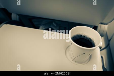 Tasse à café avec du café noir dans l'avion sur une table pliante. Boire et manger dans l'avion. Banque D'Images