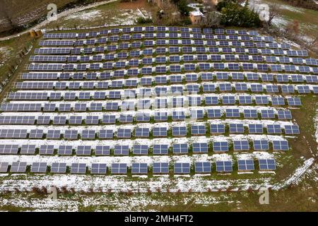 Panneau photovoltaïque à cellule solaire dans un paysage de campagne enneigé sur fond de ciel ensoleillé et de montagne. Banque D'Images