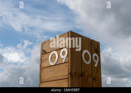 Le numéro neuf en acier inoxydable sur fond de bois contre le ciel. 09 Banque D'Images