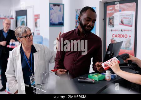 Client afro-américain mettant des produits pharmaceutiques sur le comptoir, se préparant à payer pour le traitement. Client adulte prenant des boîtes de pilules et de suppléments de pharmacie, service de médecine Banque D'Images