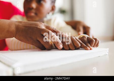 Bonne grand-mère afro-américaine et petite-fille aveugle lisant le braille Banque D'Images