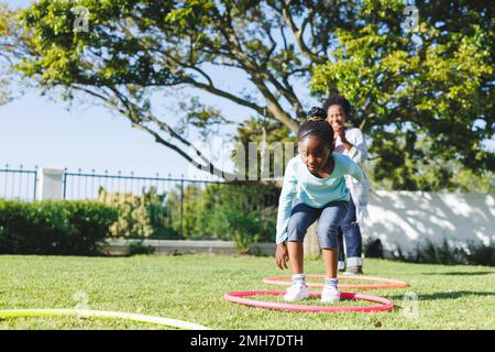 Bonne grand-mère afro-américaine et petite-fille utilisant la hula houle dans le jardin Banque D'Images