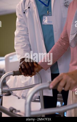 Gros plan d'un médecin afro-américain et d'un patient caucasien âgé tenant les mains Banque D'Images