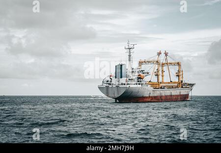 Vue depuis l'arrière d'un énorme cargo dans l'océan avec deux grues de fret sur lui; un gros cargo dans les eaux ouvertes avec un espace de copie sur la gauche; un Banque D'Images