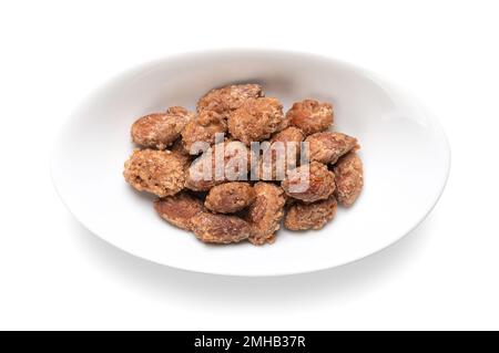 Amandes confites dans un bol ovale blanc. Fait maison, d'une manière spéciale amandes cuites, noix entières enrobées de sucre croquant. Vendu sur les marchés de Noël. Banque D'Images