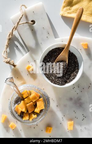 Un gâteau au pudding au chia de mangue sur un plateau en marbre avec un bol de graines de chia. Banque D'Images