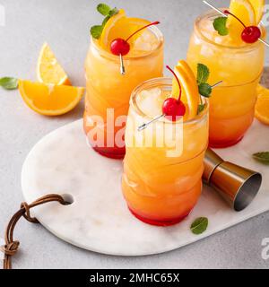 Punch au rhum dans des verres tiki avec des tranches d'orange et une cerise Banque D'Images