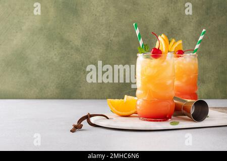 Punch au rhum dans des verres tiki avec des tranches d'orange et une cerise Banque D'Images