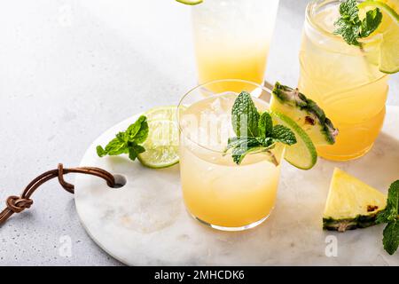 Cocktail mai tai dans différents verres garni d'ananas et de citron vert Banque D'Images