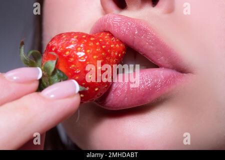 Fraise sur les lèvres. Beauté bouche. Fraise rouge dans la bouche de la femme gros plan. Banque D'Images