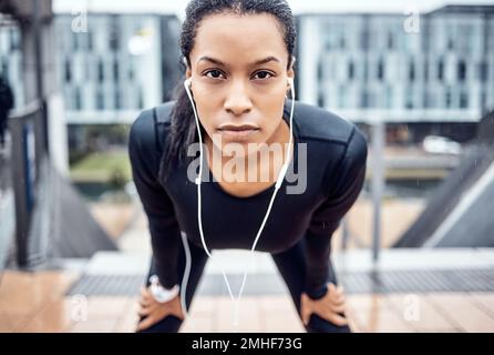 Portrait, fatigué et sérieux avec une femme noire de sport prenant un repos de son entraînement d'exercice dans la ville. Visage, musique et fitness avec une jeune femme Banque D'Images