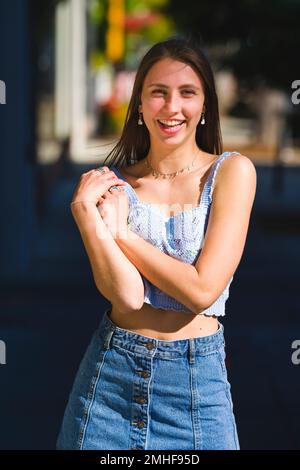 Belle jeune fille souriante debout sur le trottoir du centre-ville de Palo Alto vêtue de Summertime Crop Top et de la jupe courte en Jean Banque D'Images