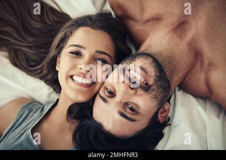 Jeune et amoureux. un jeune couple affectueux se détendant au lit ensemble. Banque D'Images