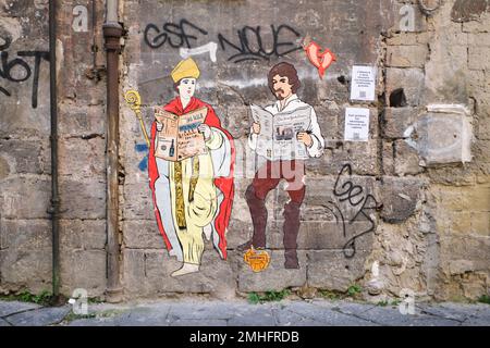 Deux affiches sur papier, représentant Saint Gennaro et l'artiste Caravaggio, lisant tous deux des journaux. Un exemple de graffiti à Naples, Naples, Italie, Italie. Banque D'Images