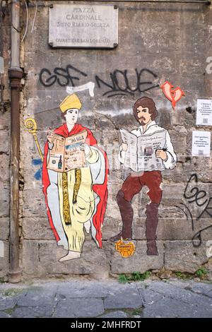 Deux affiches sur papier, représentant Saint Gennaro et l'artiste Caravaggio, lisant tous deux des journaux. Un exemple de graffiti à Naples, Naples, Italie, Italie. Banque D'Images