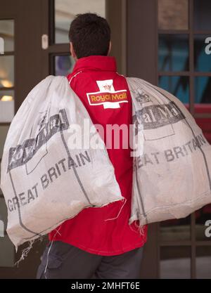 Photo du dossier datée du 16/09/13 d'un postier transportant des sacs de courrier. On estime que 31 millions de personnes ont été touchées par des retards de lettres à Noël, alors que Royal Mail « laisse les consommateurs tomber pour une troisième année consécutive », a déclaré les conseils des citoyens. Banque D'Images