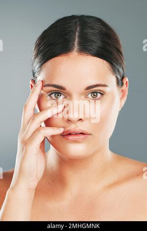 Femme, beauté et portrait en studio pour les soins de la peau, le bien-être et les cosmétiques du visage. Jeune femme modèle touchant le visage, maquillage esthétique et dermatologie Banque D'Images