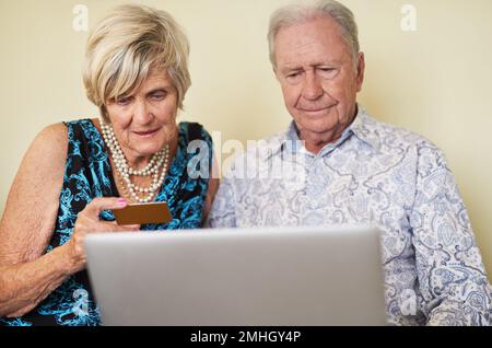 Maintenir leur liberté financière avec la technologie moderne. un couple senior effectuant un paiement par carte de crédit sur un ordinateur portable ensemble à la maison. Banque D'Images