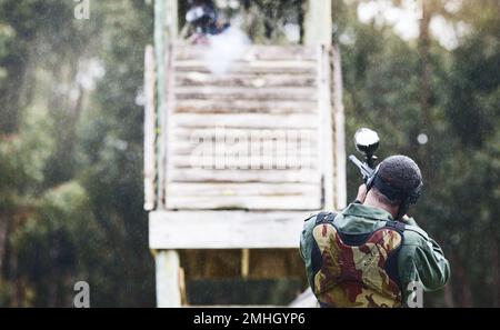 Paintball, pistolet ou homme avec une cible dans un jeu de tir avec action rapide sur un champ de bataille amusant en vacances. Mission militaire, visée ou joueur avec des armes Banque D'Images