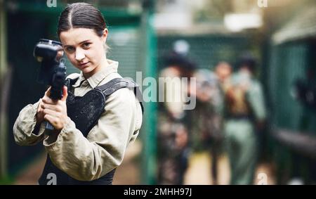 Portrait de paintball, femme et arme à feu visent dans l'arène de jeu, le leadership ou le travail d'équipe sportif en uniforme militaire. Joueur, tireur et fusil de jeu pour Banque D'Images