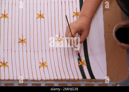 Une femme fait des croquis à la main avec des outils de cantage et de la cire chaude pour faire Batik traditionnel Banque D'Images