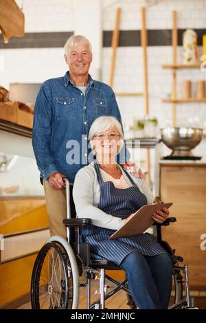 N'étaient pas encore prêts à prendre leur retraite. Portrait de deux propriétaires d'entreprise confirmés heureux se posant ensemble à l'intérieur de leur café-restaurant. Banque D'Images