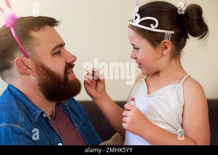 Futur maquilleur dans la fabrication. une adorable petite fille qui met du maquillage sur son père à la maison. Banque D'Images