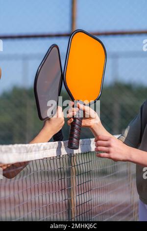 Les palettes de Pickleball se rapprochent des mains des enfants, des activités sportives de plein air. Banque D'Images