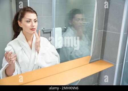 Une jeune femme charmante est debout dans la salle de bains de l'hôtel Banque D'Images