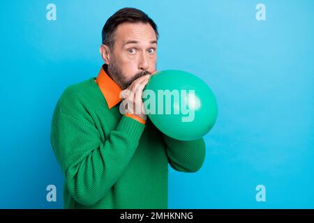 Photo portrait d'un homme mûr beau souffle air ballon shopping promo habillé élégant vert tenue isolée sur fond bleu couleur Banque D'Images