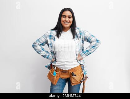 Portrait d'une jeune femme indienne forte sur le point de faire du bricolage à la maison avec la ceinture à outils Banque D'Images