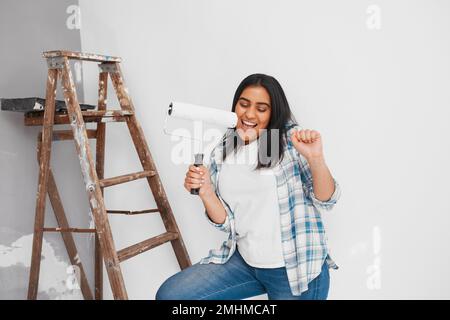 Gros plan de la jeune femme chantant et dansant tout en peignant mur maison bricolage Banque D'Images