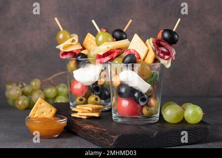 Jarcuterie en deux verres comprend différents types de saucisses, de cornichons, de fromage, de noix, de légumes et de fruits. Version moderne d'en-cas festifs Banque D'Images