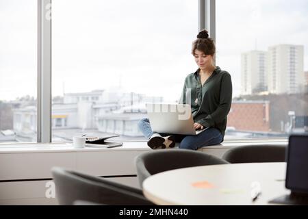 Businesswoman using laptop in office Banque D'Images