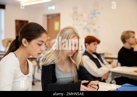 Les adolescentes qui utilisent le téléphone en classe Banque D'Images