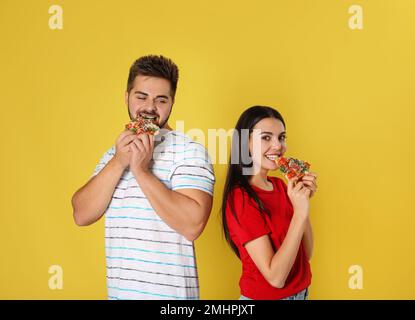 Jeune couple mangeant de la pizza sur fond jaune Banque D'Images