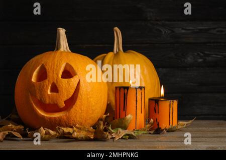 Citrouilles et bougies allumées sur fond en bois noir. Décoration traditionnelle pour Halloween Banque D'Images