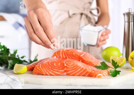 Femme salant du saumon frais à la table, en gros plan.Délicatesse du poisson Banque D'Images