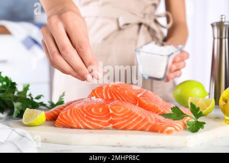 Femme salant du saumon frais à la table, en gros plan.Délicatesse du poisson Banque D'Images